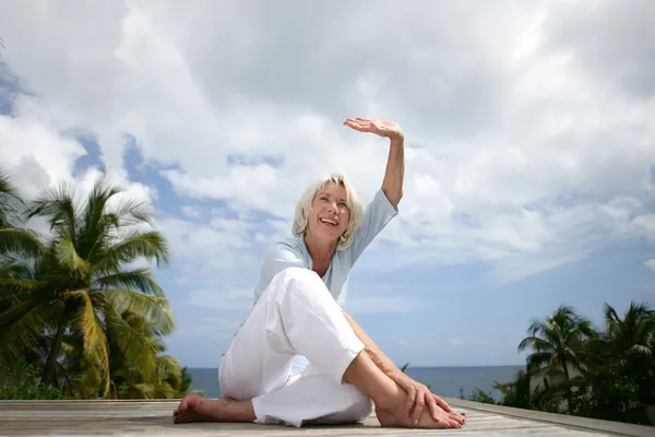 Seniorin macht im Urlaub Übungen — Stockfoto