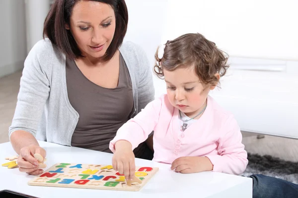 Mor och dotter att slutföra ett brev pussel — Stockfoto