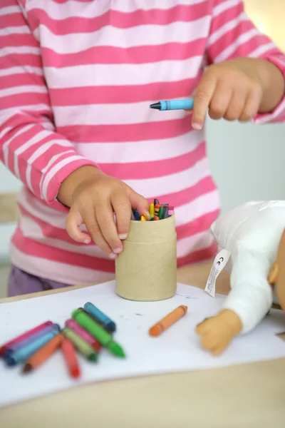 Маленька дівчинка малює восковими олівцями — стокове фото