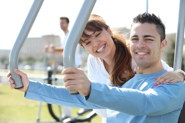 Smiling woman and man using fitness machines Stock Photo