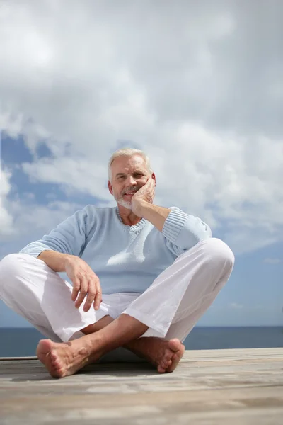 Grey haired man sat on jetty — Stock Photo, Image