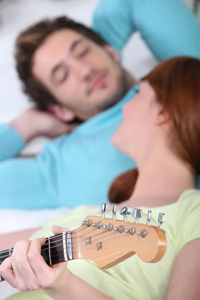 Pareja tocando una guitarra en casa — Foto de Stock