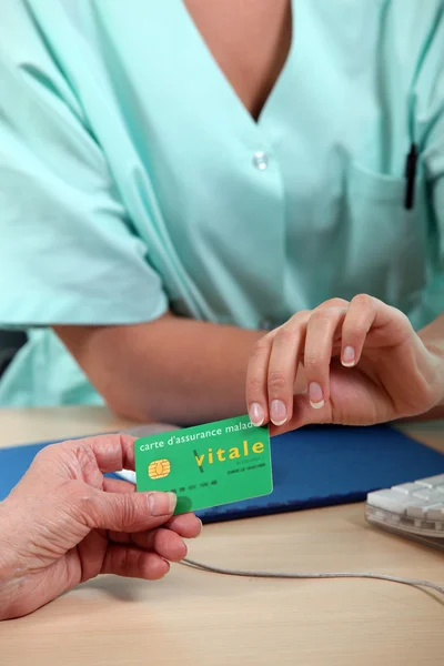 Health insurance card being passed from patient to medical staff — Stock Photo, Image