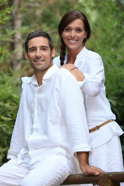 Pareja sonriente vestida de blanco en un jardín —  Fotos de Stock