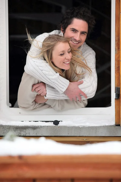 Para przytulanie przez okno chalet — Zdjęcie stockowe