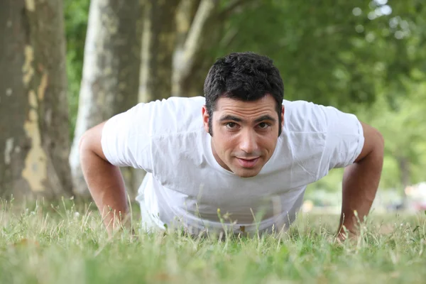 Man doing press ups in the park — Stock Photo, Image