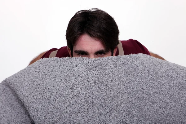 Człowiek chowający się za rolką dywanu — Zdjęcie stockowe