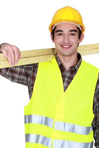 Retrato de jovem marceneiro transportando pranchas sobre o ombro — Fotografia de Stock