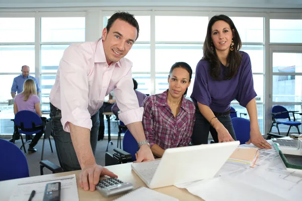 Equipe criativa trabalhando em torno de um laptop — Fotografia de Stock