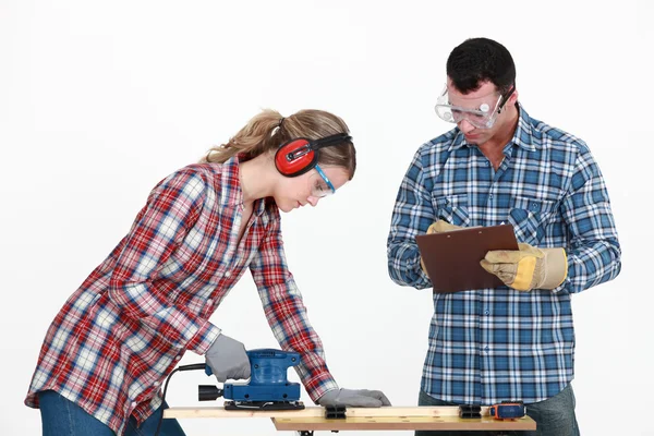 Man evaluating a tradeswoman on her use of a jigsaw — Zdjęcie stockowe