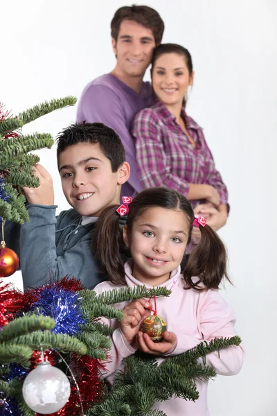 Padres felices con niños decorando el árbol de Navidad —  Fotos de Stock