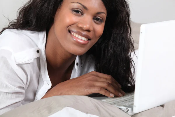 Afrikaanse vrouw liggen en plezier met haar laptop — Stockfoto