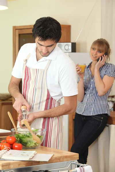 Husband cooking whilst wife telephones — Stock Photo, Image