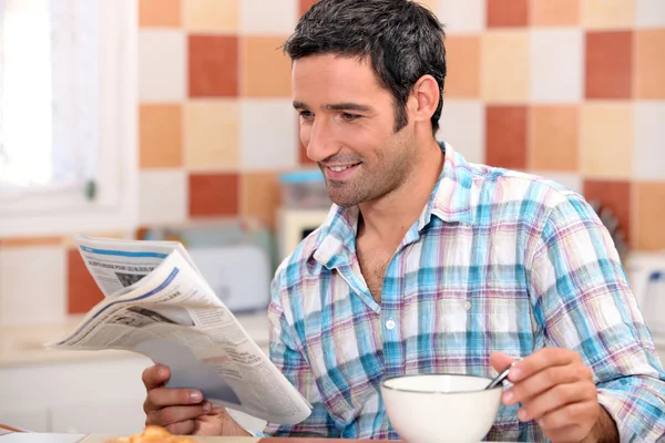 Черный человек завтракает с газетой — стоковое фото