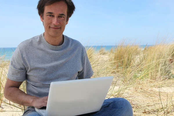 Людина на пляжі з ноутбуком — стокове фото