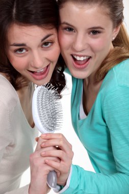 Two teenagers singing with a brush. clipart