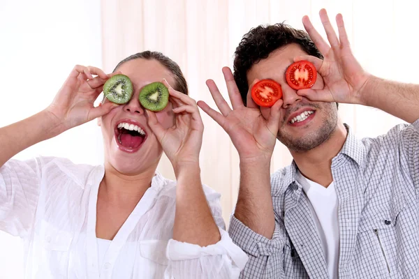 Pareja sosteniendo fruta a sus ojos — Foto de Stock