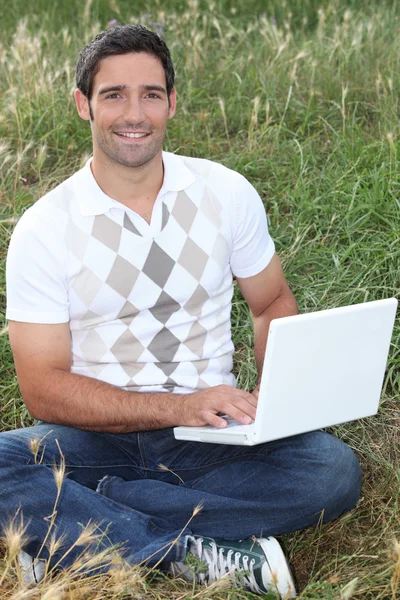 Mannen satt i fält med bärbar dator — Stockfoto