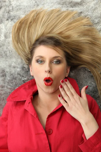 Surprised woman lying on a carpet — Stock Fotó