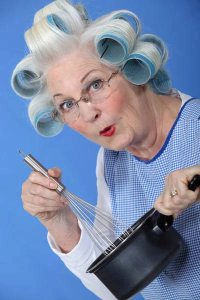 Mulher sênior com encrespadores em seu cabelo cozinhar — Fotografia de Stock