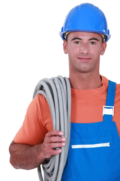 Comerciante llevando tubos corrugados alrededor de su hombro — Foto de Stock