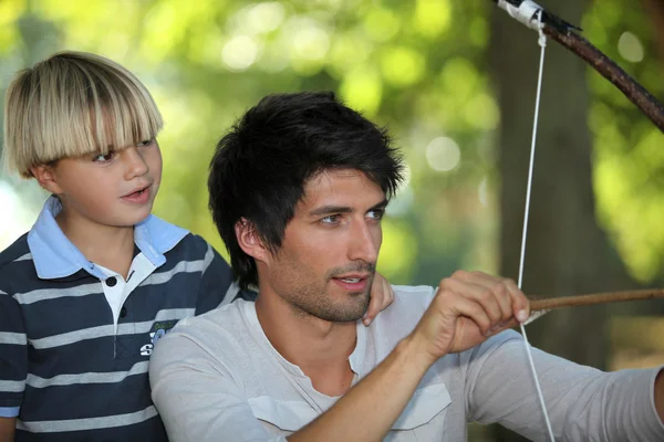 Père enseignant à son fils comment tirer un arc et une flèche — Photo