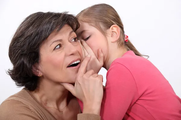 Una niñita contándole un secreto a su madre . — Foto de Stock