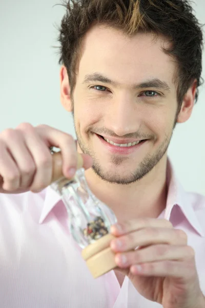Young man holding a pepper shaker — Stock Photo, Image