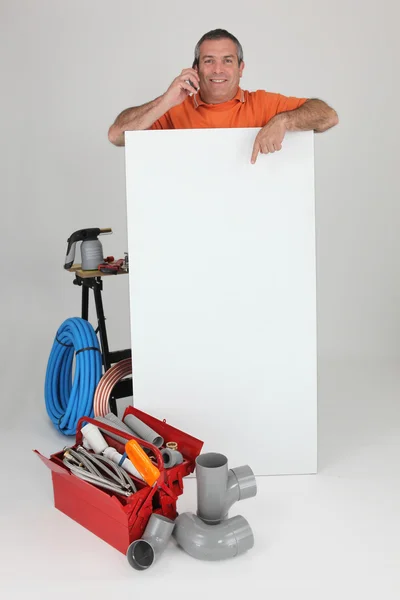 Plumber on the phone with a board left blank for your message — Stock Photo, Image