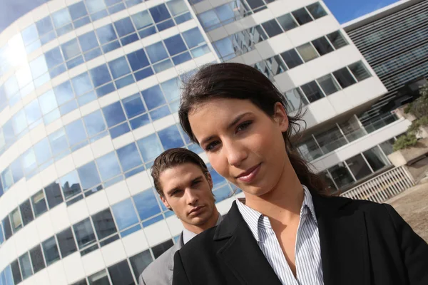 Jovem casal de ternos em pé fora de um prédio de escritórios — Fotografia de Stock