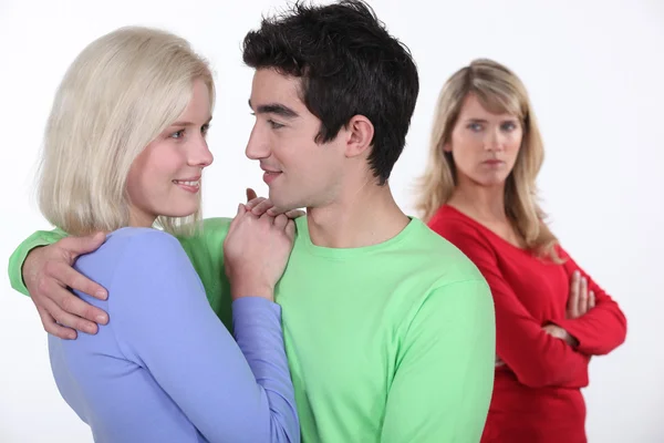 Donna gelosa che guarda un uomo che abbraccia una giovane donna — Foto Stock