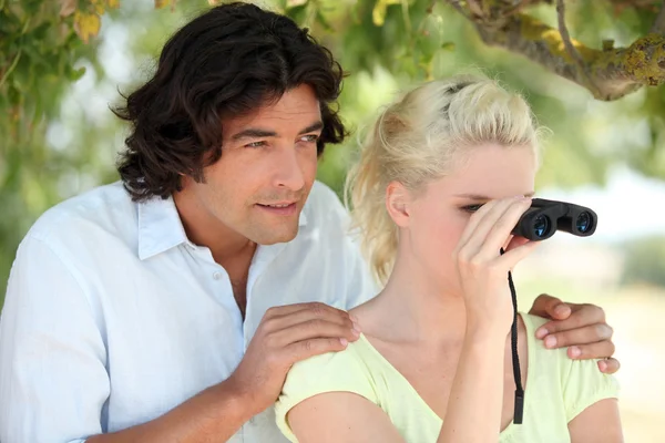 Young woman with binoculars and boyfriend — Stock Photo, Image