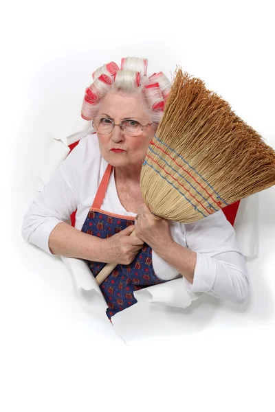 Mujer mayor enojada con rulos en el pelo sosteniendo una escoba — Foto de Stock