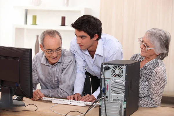 Unga hjälpande senior med dator — Stockfoto