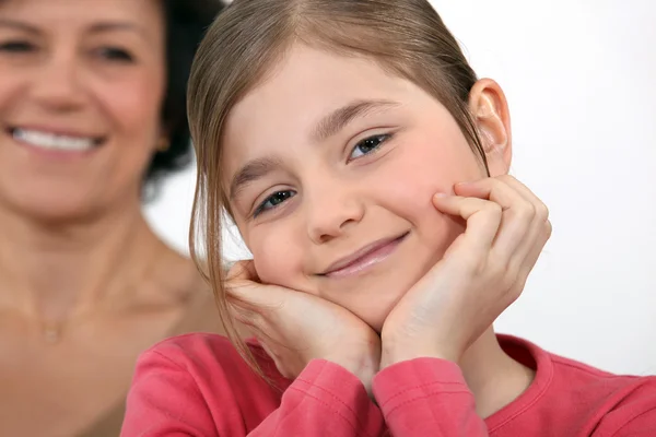 Una niña posando con su madre en el fondo . — Foto de Stock