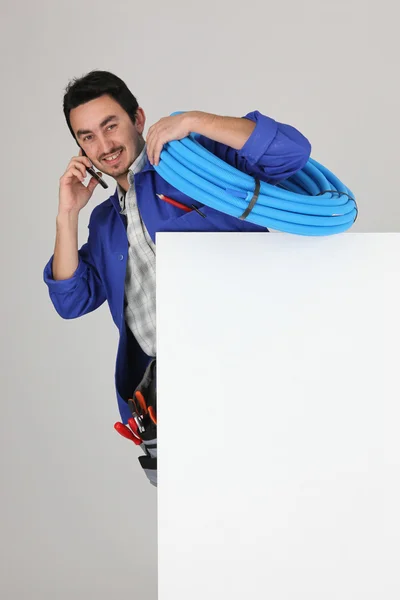 Craftsman talking on the phone behind an empty poster board — Stock Photo, Image