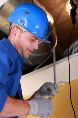 Electrician working by exposed ceiling panel clipart