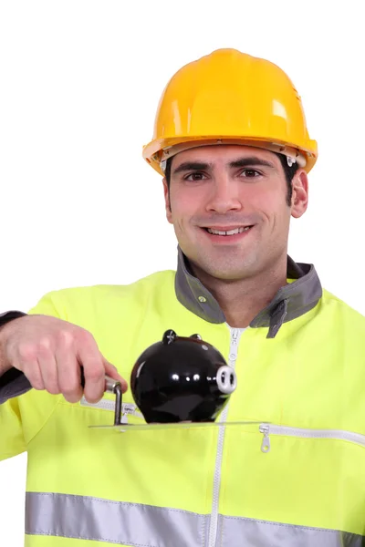 Um pedreiro segurando um banco porquinho . — Fotografia de Stock