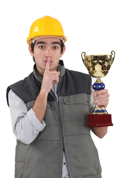 Um trabalhador da construção civil que faz barulho enquanto tem uma taça de troféu na mão . — Fotografia de Stock