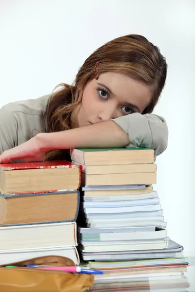 Jovem mulher colocando a cabeça em uma pilha de livros — Fotografia de Stock