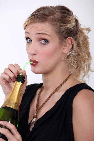 Kvinna dricker champagne genom ett sugrör — Stockfoto