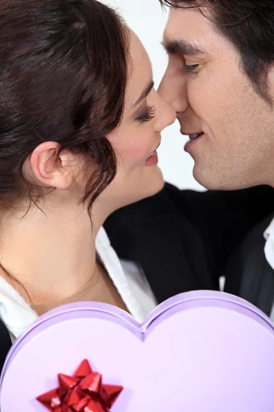 Homem oferecendo namorada caixa em forma de coração de chocolates — Fotografia de Stock