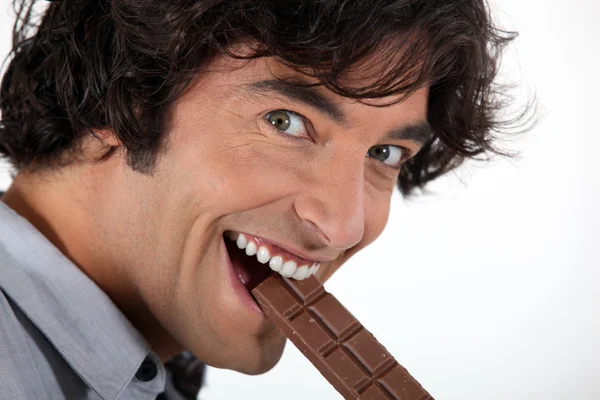 Man biting into chocolate bar — Stock Photo, Image