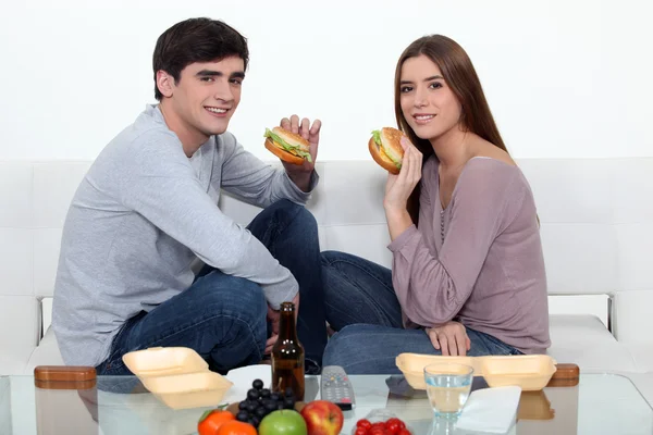 Homem e mulher comendo hambúrgueres — Fotografia de Stock