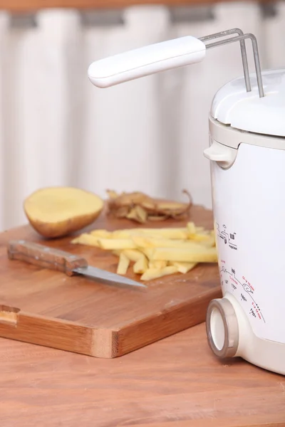 Potatoes and electric fryer — Stock Photo, Image