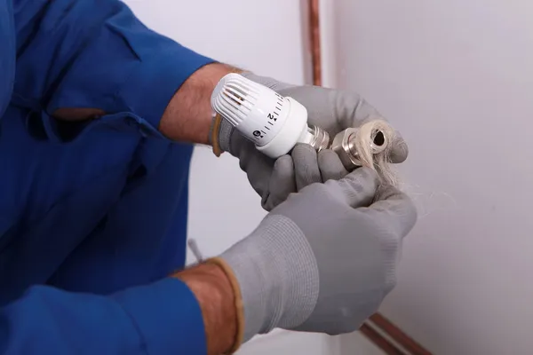 Plombier utilisant du chanvre ou une fibre similaire pour imperméabiliser un joint — Photo