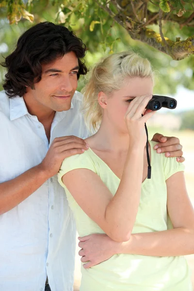 Casal usando par de binóculos — Fotografia de Stock