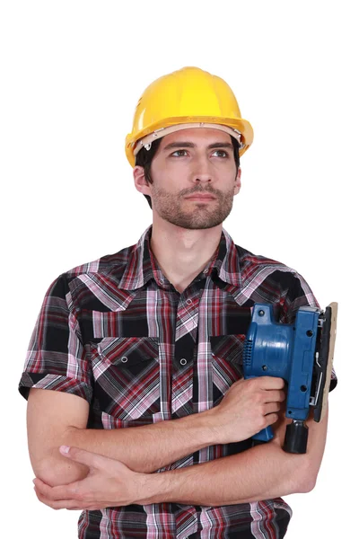 Um trabalhador da construção civil com uma máquina de lixar . — Fotografia de Stock