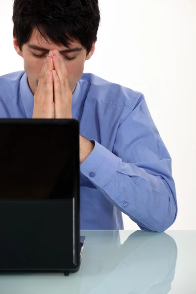 Νεαρός επιχειρηματίας που κάθεται μπροστά από το φορητό υπολογιστή, κοιτάζοντας εξαντλημένοι — Φωτογραφία Αρχείου