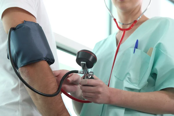 Doctor taking blood pressure to patient — Stock Photo, Image